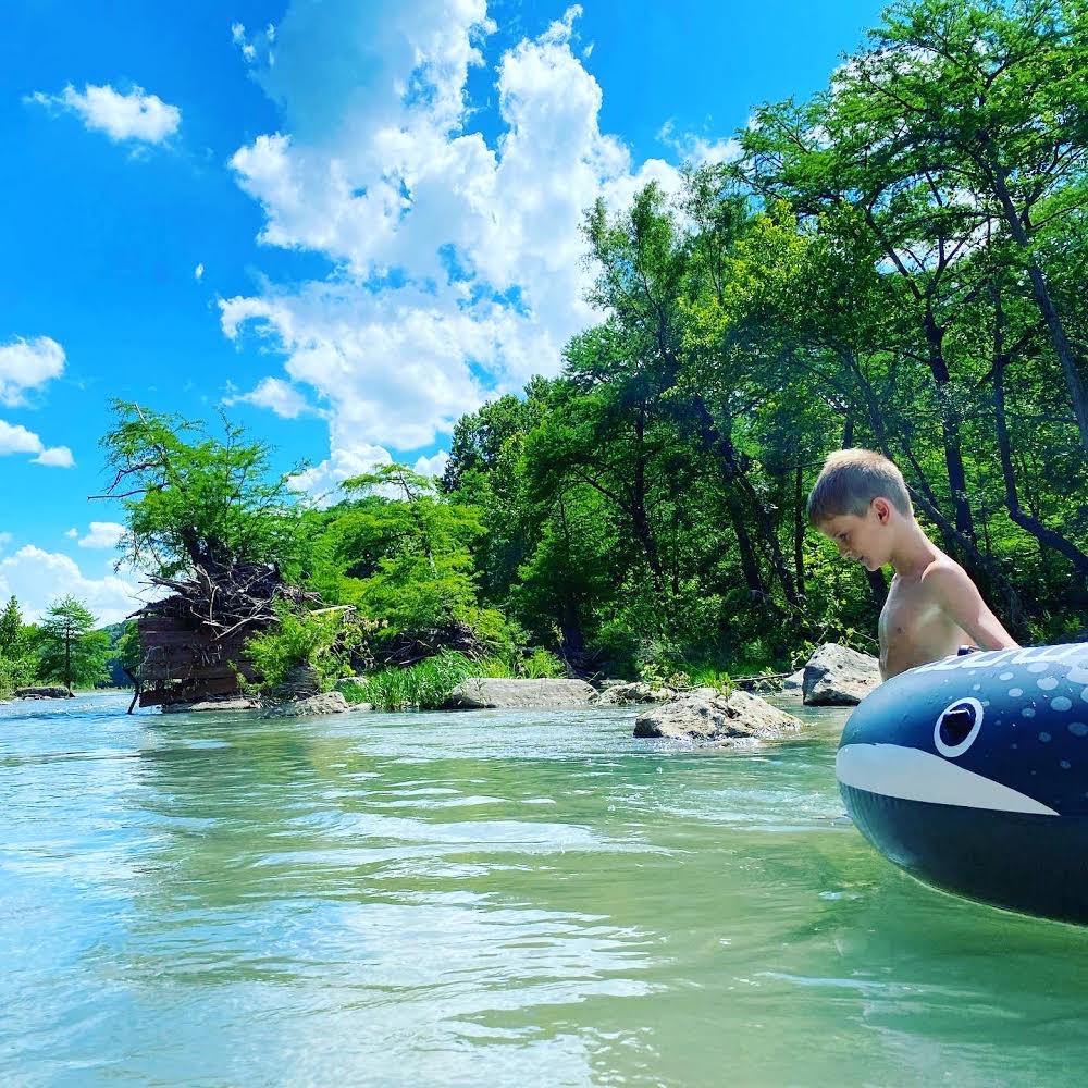 Kid floating on a whale tube in the river